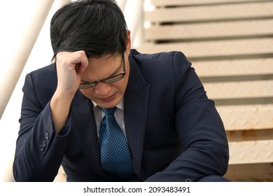 Bankruptcy Layoff Asian Businessman Stress Headache Sitting On Stairs Step. Failed Sad Unemployed Pain Anxiety Asia People Man Jobless Worried Problem Economic Sitting Outdoor. Person Failure Concept.