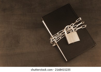 Banned information and secure concept, book with chain and padlock on wooden table. Copy space for text