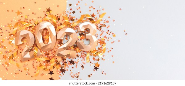 Banner with 2023 golden numbers, ribbons and stars confetti on a blue background. Glittering New Year's concept with place for text. - Shutterstock ID 2191629137