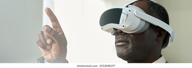 Banner of aged African American businessman with virtual reality headset pointing at augmented visual board while making presentation - Powered by Shutterstock