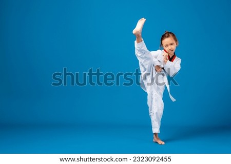 Banner: Asian-Australian girl poses in martial arts Practice taekwondo, karate, judo against a blue background in the studio. Asian kids karate or Taekwondo martial arts. Sport kid training action.