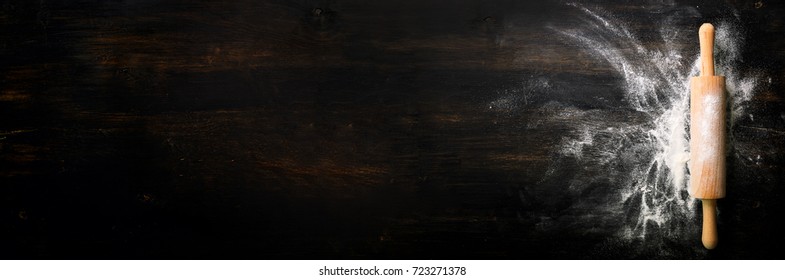 Banner. Baking background with free space for your text. Rolling pin and flour on black table. Copy space. Top view