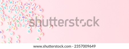 Banner with beads with letters scattered on a pink background. Creative concept.
