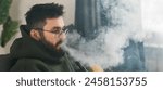 Banner bearded millennial or gen z man smoking hookah while relaxing on sofa at home copy space - chill time and resting concept