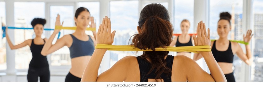 banner of brunette pilates trainer with resistance band showing exercise to group of diverse women - Powered by Shutterstock