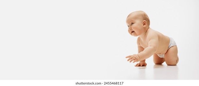 Banner. Charming little baby-girl in diaper crawls with playful expression against white studio background with negative space to insert text. Concept of childhood, motherhood, life, birth. Ad