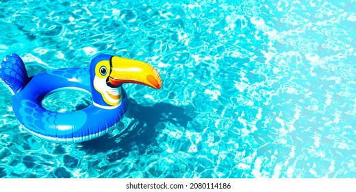 Banner With Children Inflatable Lifebuoy Rubber Swim Ring Of Colorful Toucan Bird Form Floats On The Blue Water Surface In Swimming Pool At Resort Hotel. Safety For Kids. Family Hotel Business