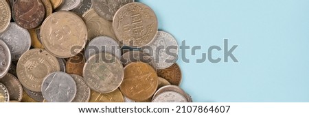 Banner with coins on blue background with copy space. Various vintage coins from worldwide as background. Coins from Korea, Turkey, Japan etc. Business concept. Numismatics, coins collecting