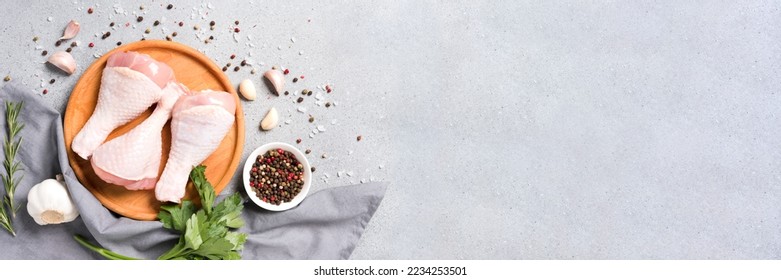 Banner with copy space - raw chicken legs on wooden plate with seasonings over gray concrete background. Chicken drumsticks ready to cook. Dietary meat, healthy eating concept - Shutterstock ID 2234253501