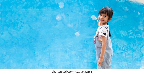 Banner Of Cute 5 Years Old Asian Little Girl Is Smiling While Painting The Wall With Water Color At Home, Concept Of Art Education For Kid, Homeschooling And Learning Activity By Playing For Child.