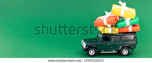 banner with\
Dark green car model with Christmas gifts on a green background.\
Delivery gift box. Concept speed delivery gifts, Christmas and Xmas\
gift concept.Copy space.