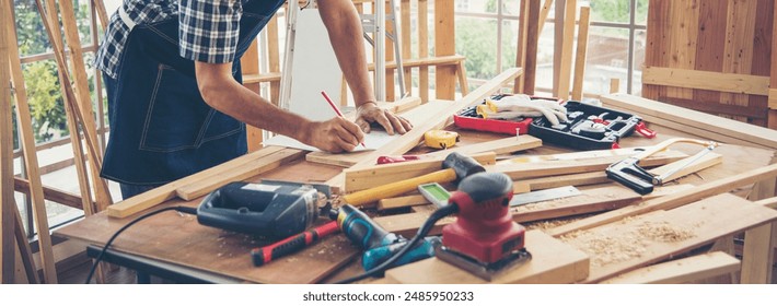 Banner DIY craftsperson asian man working wood heap carpenter objects woodwork desk. Banner Architect man hands ruler measure home improvement. Wood carpenter construction workshop with copy space - Powered by Shutterstock