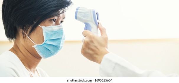 Banner Of Doctor Check Asian Woman Body Temperature Using Infrared Forehead Thermometer (thermometer Gun) For Virus Symptom At Hospital. Corona Virus, Covid-19, Quarantine Or Virus Outbreak Concept