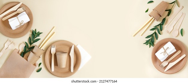 Banner with eco craft paper tableware and wooden cutlery on beige background with copy space. Top view