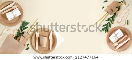 Banner with eco craft paper tableware and wooden cutlery on beige background with copy space. Top view