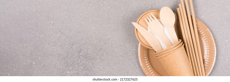 Banner With Eco Utensils - Paper Plates And Cups, Wooden Cutlery Set And Drinking Straws Over Concrete Background With Copy Space For Text. Sustainable Food Packaging, Catering. Selective Focus