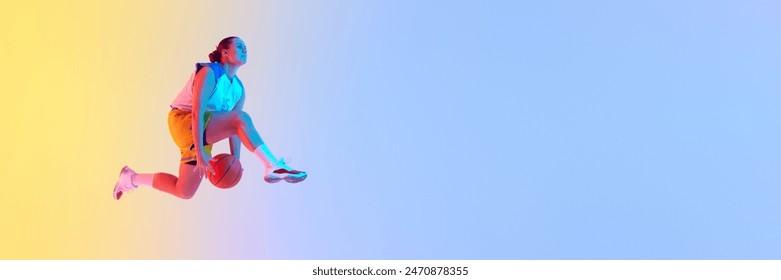 Banner. Focused on game young woman, basketball player dribbling in mid-air in neon light against gradient studio background. Concept of professional sport, championship, tournament, recreation. Ad - Powered by Shutterstock