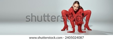 banner of glamorous model in red attire with high heels and bright tights posing on grey background