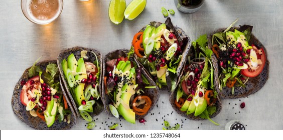 banner of Gluten-free vegan tacos from black bean  with tomato and avocado salad  with tahini sauce and pomegranate seeds. healthy fast food for the whole family or party and beer - Powered by Shutterstock