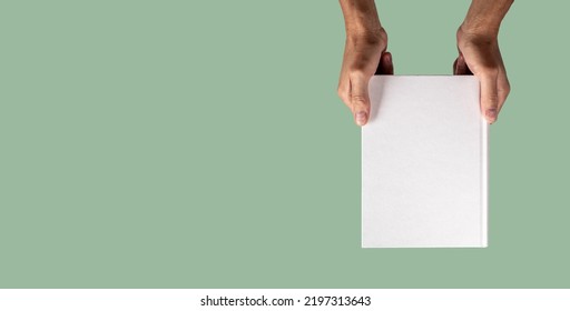 Banner With Hand Holding Closed Book Mockup On Green Background In Eco Style. Template With Blank Cover About Weather, Nature, Ecology, Biology. Space For Text. High Quality Photo