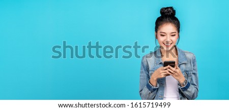 Banner of Happy asian woman feeling happiness and standing typing smartphone on blue background. Cute asia girl smiling wearing casual jeans shirt and connect internet shopping online and surfing.
