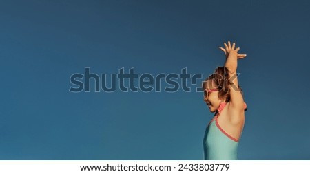 Banner happy laughing child girl of 5 years in wet blue swimsuit and sunglasses put her hands up for dive, fine against sky, lifestyle, copy space, goal attainment concept
