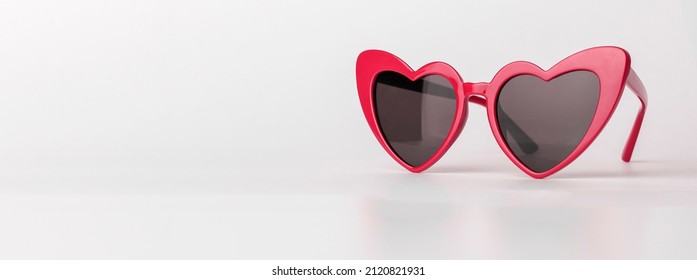 Banner with heart-shaped sun glasses. Valentines red sunglasses on background with copy space. High quality photo