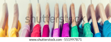 Banner horizontal crop for text background of clothing rack. Clothes for women hanging on hangers in home closet or shopping mall for store sale concept. Colorful selection of t-shirts.