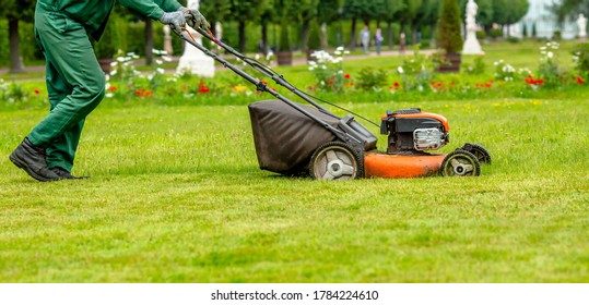 Banner. A human lawn mower cuts the grass in the backyard. Agricultural machinery for the care of the garden.