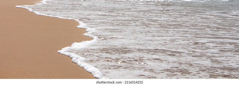 Banner of incoming foamy wave and clean water surface with clean, smooth and beige sand of summer beach, side view. Perfect summer background.