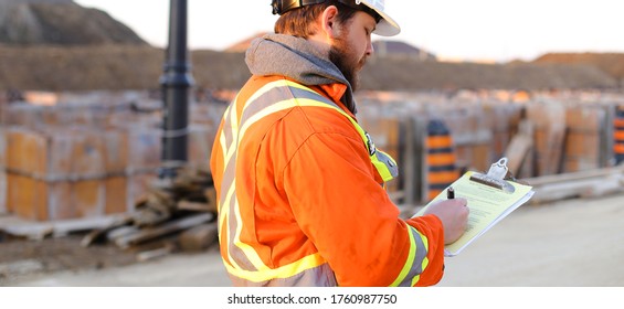 Banner of inspector in orange workwear with blueprints and notebook on construction site. Concept of builder profession and foreman .