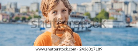 BANNER, LONG FORMAT Boy in Istanbul having breakfast with Simit and a glass of Turkish tea. Glass of Turkish tea and bagel Simit against golden horn bay and the Galata Tower in Istanbul, Turkey