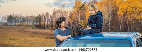 BANNER, LONG\
FORMAT Dad and son are resting on the side of the road on a road\
trip. Road trip with children\
concept