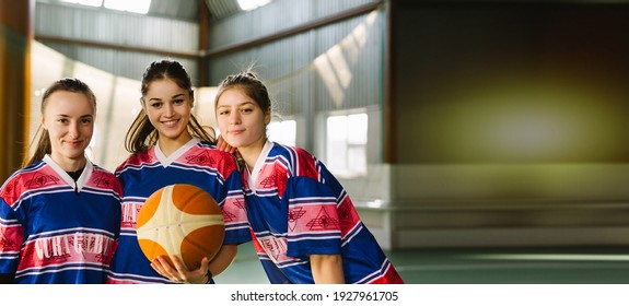 Banner- long format. Group of three sport girls, international friends in team sportswear posing to camera. Members of female high school basketball team, energetic female players celebrating win - Powered by Shutterstock