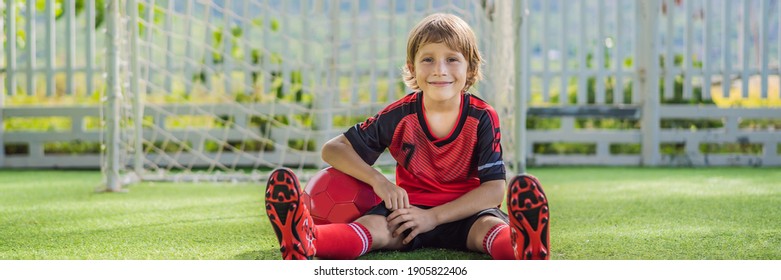 BANNER, LONG FORMAT Little cute kid boy in red football uniform playing soccer, football on field, outdoors. Active child making sports with kids or father, Smiling happy boy having fun in summer