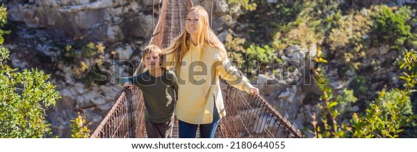 BANNER, LONG FORMAT\
Mom and son tourists on Old rusty bridge. Attraction Long extreme\
suspension iron bridge across the river Moraca. Sights of\
Montenegro. Landmark\
Montenegro