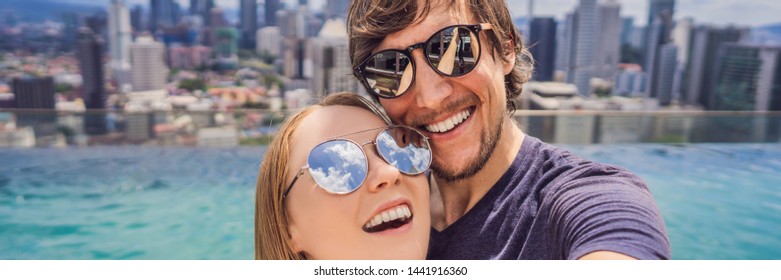 BANNER, LONG FORMAT young happy and attractive playful couple taking selfie picture together at luxury urban hotel infinity pool and panoramic view of the city enjoying holidays honeymoon travel in - Powered by Shutterstock