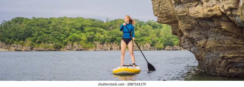 BANNER, LONG FORMAT Young Women Having Fun Stand Up Paddling In The Sea. SUP. Red Hair Girl Training On Paddle Board Near The Rocks