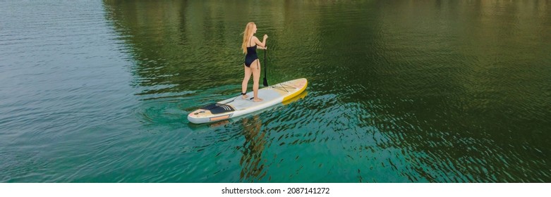 BANNER, LONG FORMAT Young Women Having Fun Stand Up Paddling In The Sea. SUP. Red Hair Girl Training On Paddle Board Near The Rocks