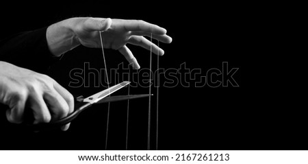 Banner with man cutting strings on fingers with scissors. Freedom, overcoming addiction, liberation from slavery, abuse, manipulation concept. Black and white. Copy space. High quality photo