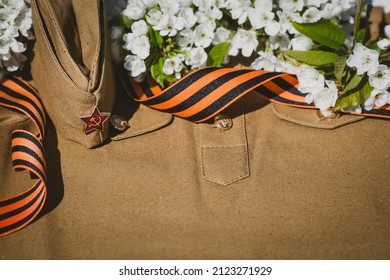 Banner For May 9. A Military Uniform, A Cap With A Star, A St. George Ribbon And A Cherry Blossom In The Background. The Concept Of The Great Victory Day 941-1945 And Defender Of The Fatherland Day.