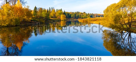 Banner with a mirror surface of the lake reflects the blue sky with clouds and yellow autumn forest