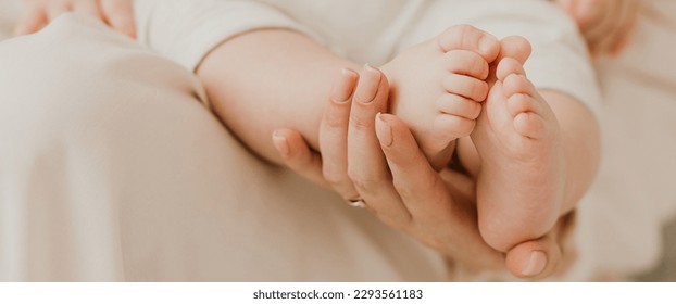 Banner. Mother holding in the hands feet of newborn baby. Baby feet in mother hands. Tiny Newborn Baby's feet on female Shaped hands closeup. Mom and her Child. Happy Family concept. 