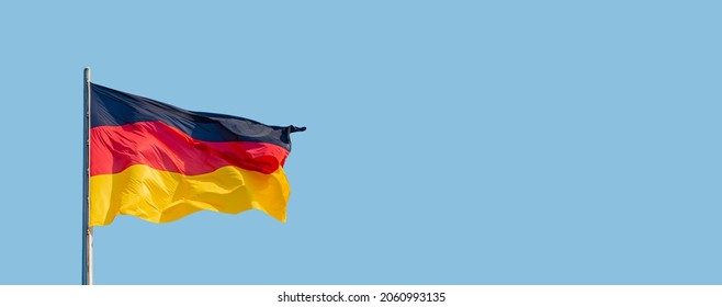 Banner with a national black red yellow flag of Germany and at blue sky background with copy space, details, closeup. Concept of nationality, citizenship and patriotism - Shutterstock ID 2060993135