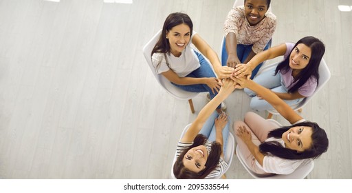 Banner With Overhead Group Portrait Of Happy Positive Smiley Beautiful Young Women Sitting Together, Holding Hands And Looking Up. Unity, Community Helping Each Other, Team Aiming For One Goal Concept