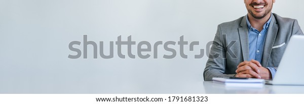 Banner panorama of\
faceless mid body section young smiling cheerful businessman\
entrepreneur in bright white modern office facing towards camera\
copy space for text