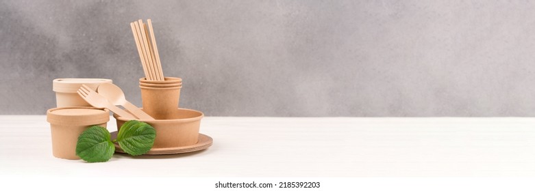 Banner With Paper Utensils - Paper Plates, Food Containers, Cups, Drinking Straws And Wooden Cutlery Set Against Gray Wall Background With Copy Space. Sustainable Food Packaging