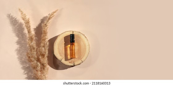 Banner Of Perfume Sample With Yellow Liquid On Wooden Tray Lying On Beige Background With Pampas Grass. Luxury And Natural Cosmetics Presentation. Tester On Woodcut In The Sunlight. Shades And Lights