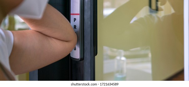 Banner Photo Of Chinese Female Wearing Medical Mask Using Elbow Press Automatic Doors Button To Open The Door Of Takeaway Restaurant. Social Distancing, Self Isolation Or New Normal Concepts