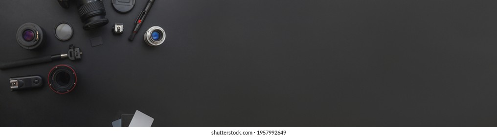 Banner. Photographer work place with dslr camera system, camera cleaning kit, lens and camera accessory on dark black table background. Hobby travel photography concept. Flat lay top view copy space